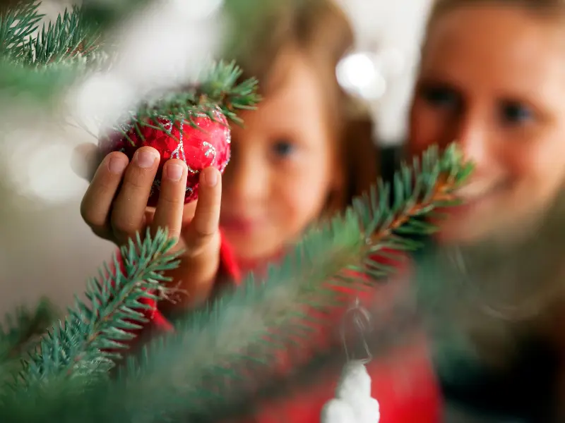 Family decorating a Christmas tree for the holidays in a foster home.